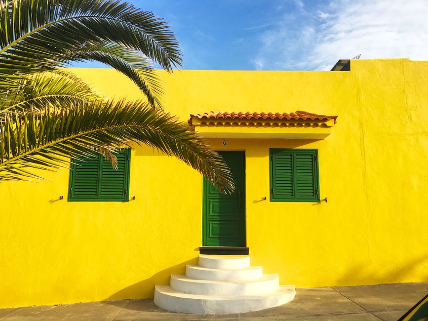 A yellow house front with green shutters.