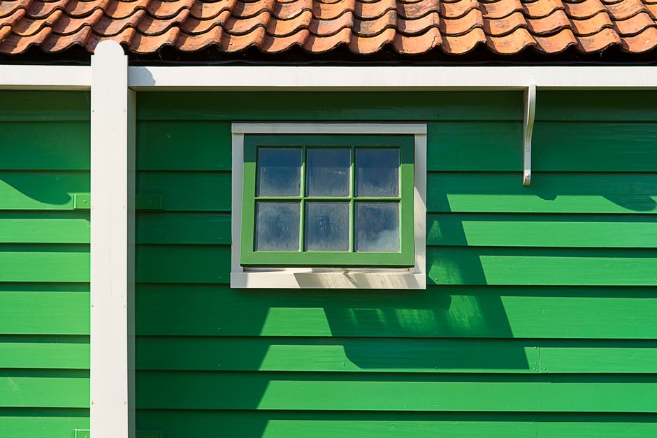 A green painted wooden house with a small window.