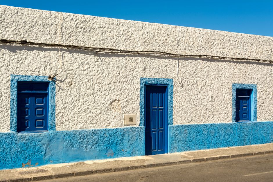 A blue and white painted house front under a clear sky.
