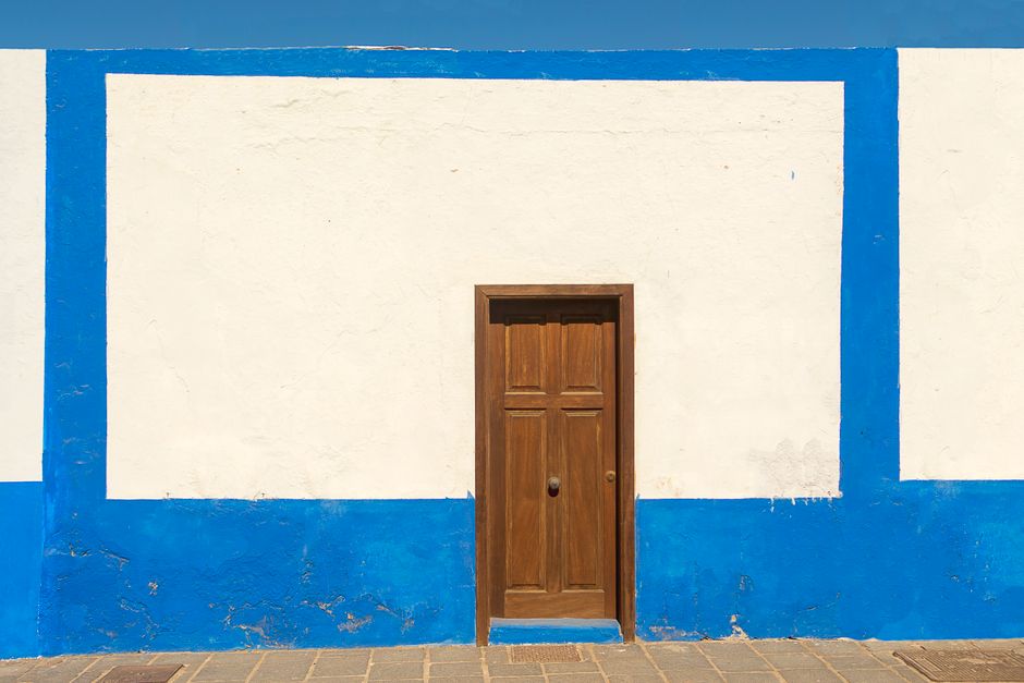 A wooden door set in a blue and white painted wall.