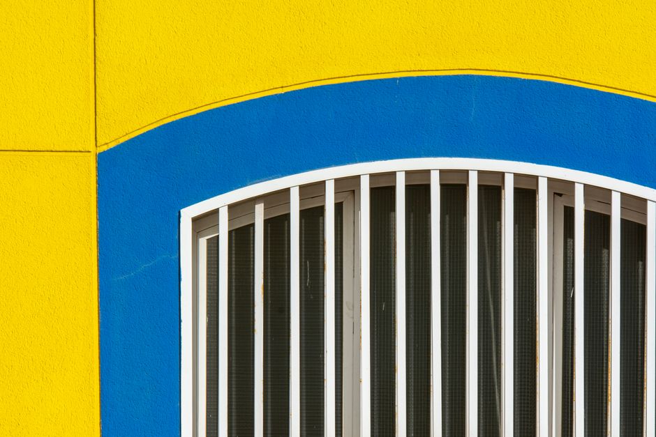 A painted yellow and blue wall around an arched window.