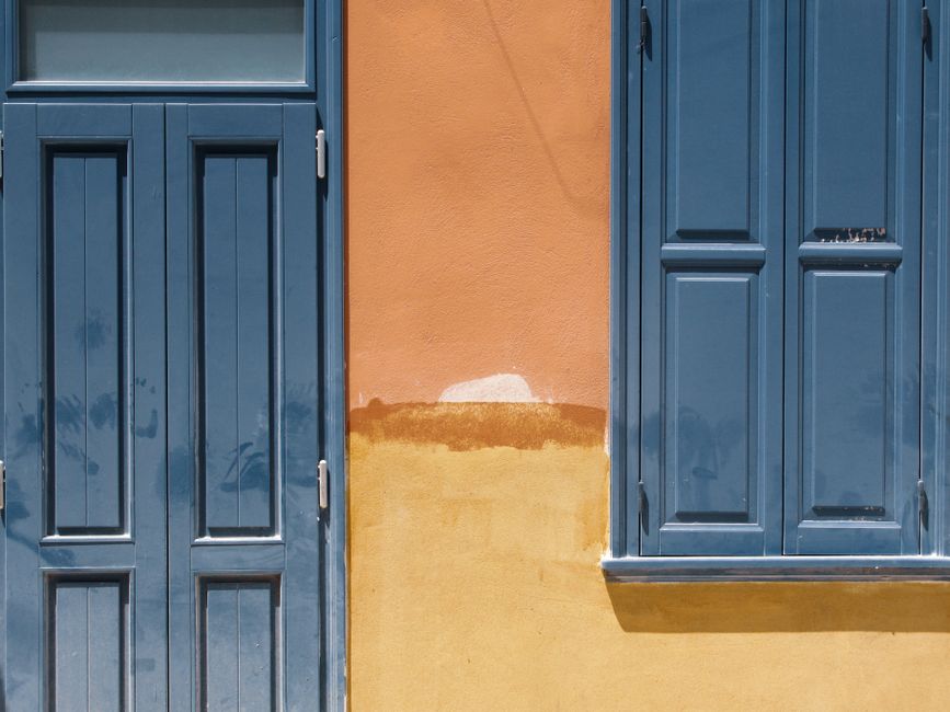 An orange painted wall with a blue door and window.