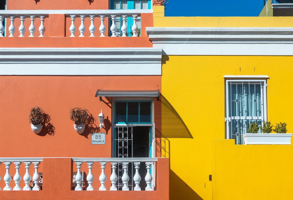 Painted orange and yellow house fronts in daylight.
