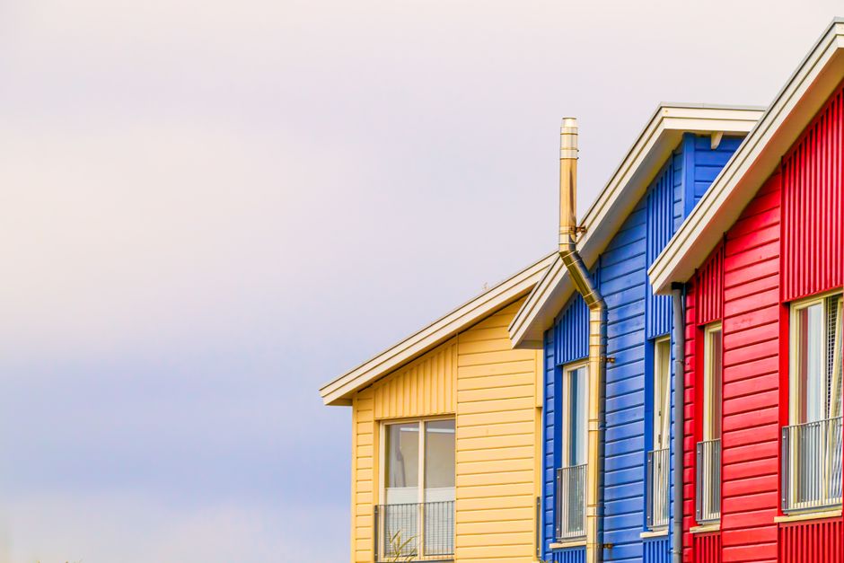 Red, blue and yellow painted house fronts under a clear sky.